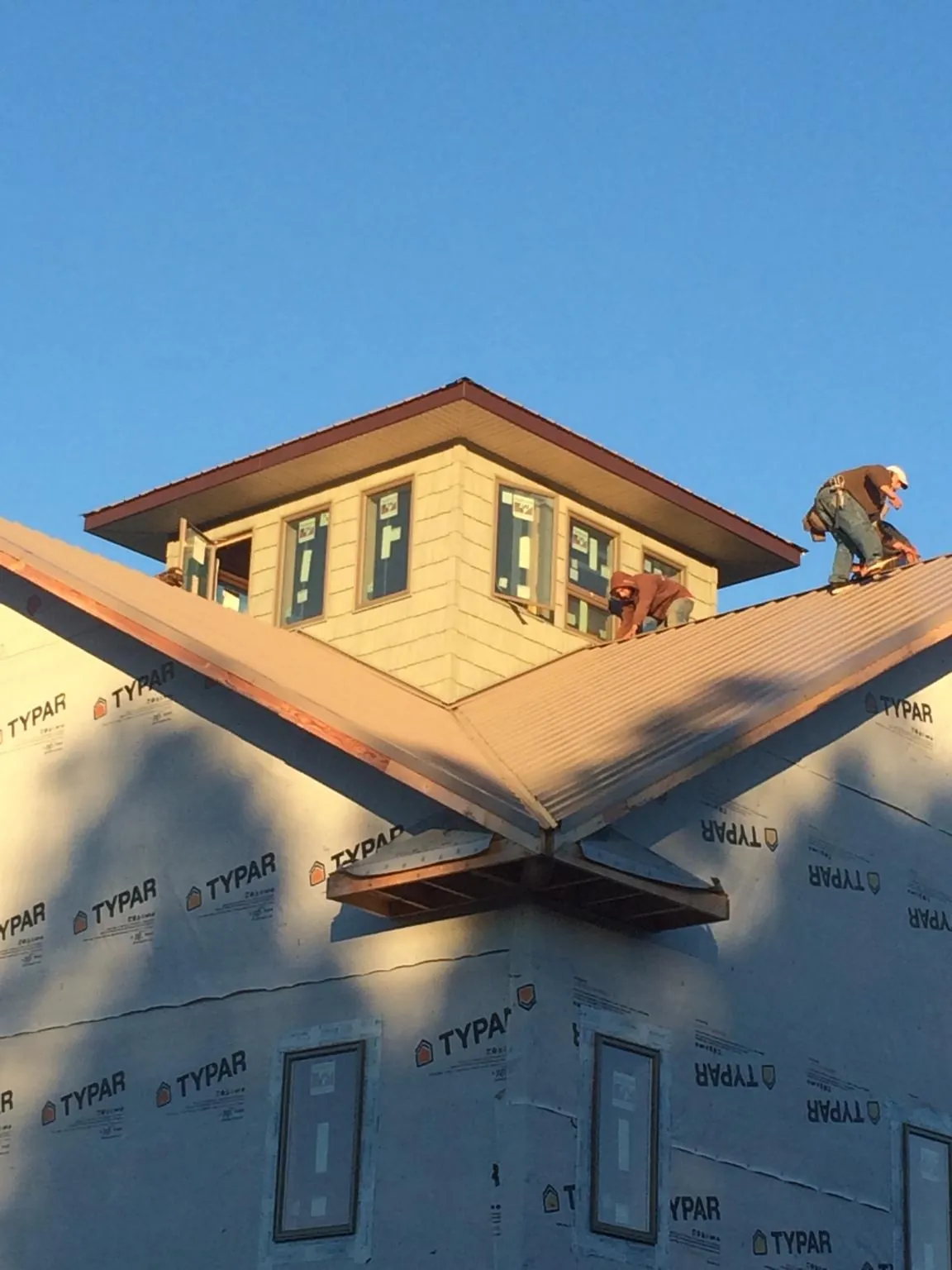 Roofers working around a rooftop cupola on a new metal roof at sunset — Roof Waterproofing in Plainfield by Roofing Brothers
